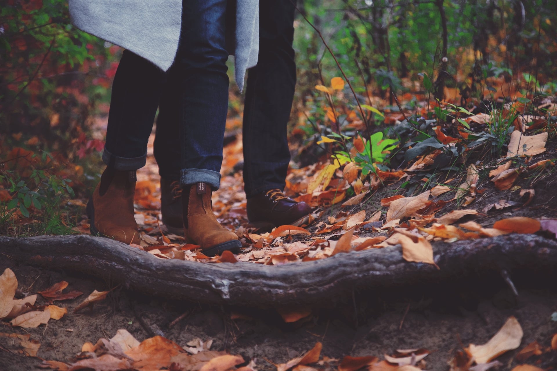 Des chaussures de marche avancent sur un sentier couvert de feuilles d’automne