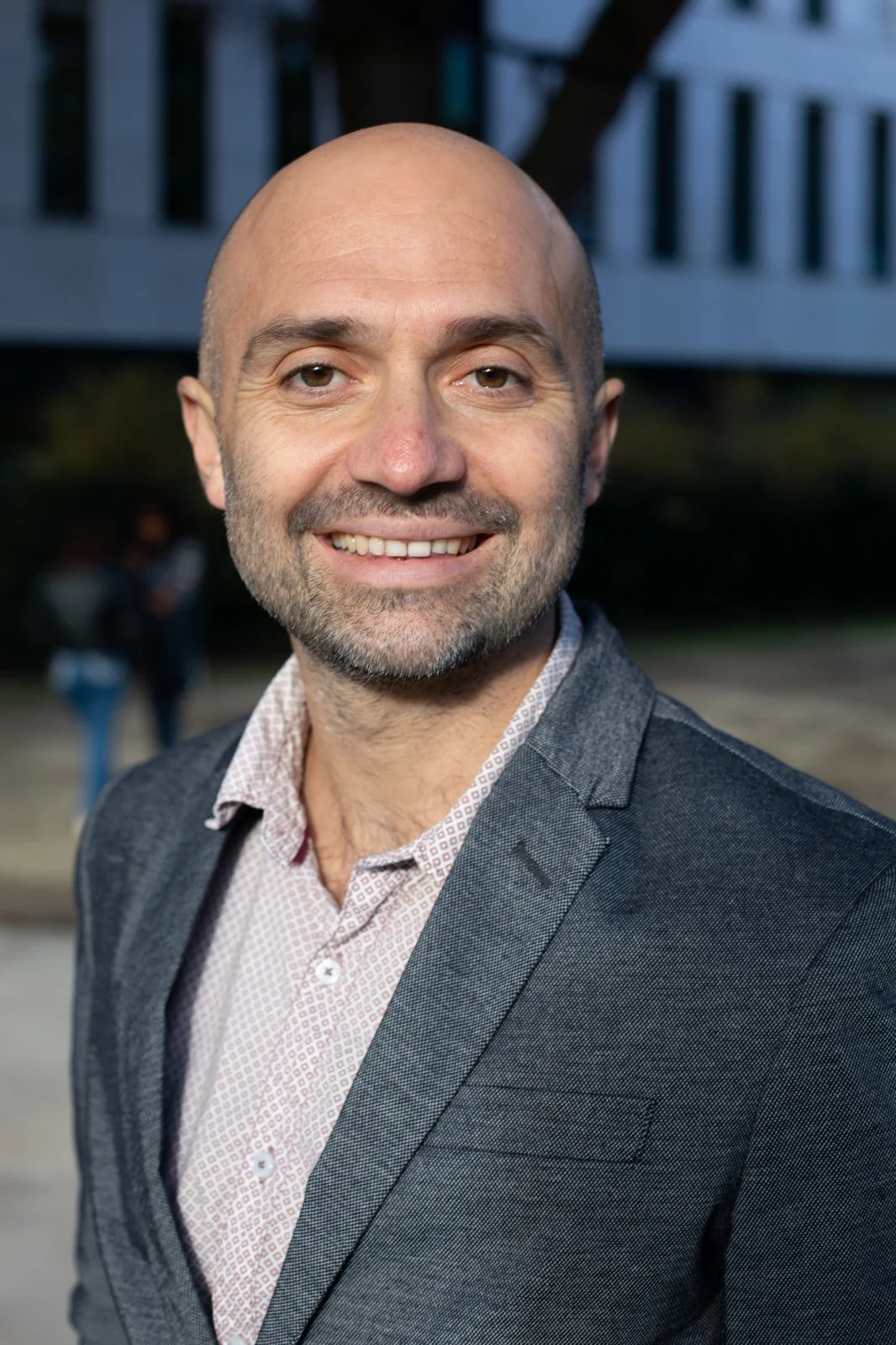 Christophe Jacques, en veste grise, sourit dans une cour arborée