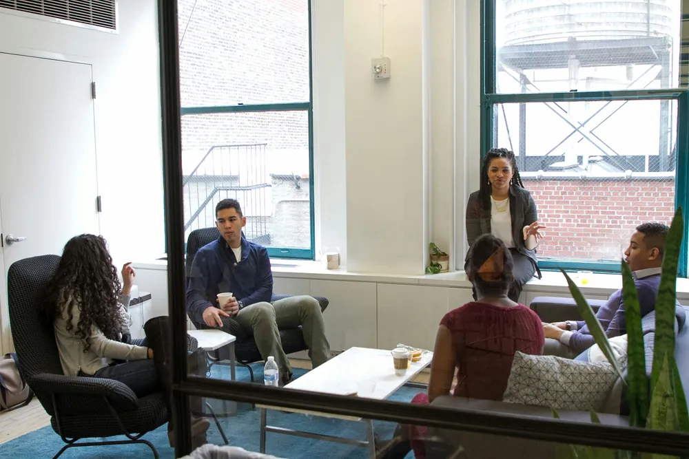 Un groupe échange, assis en cercle dans un salon lumineux