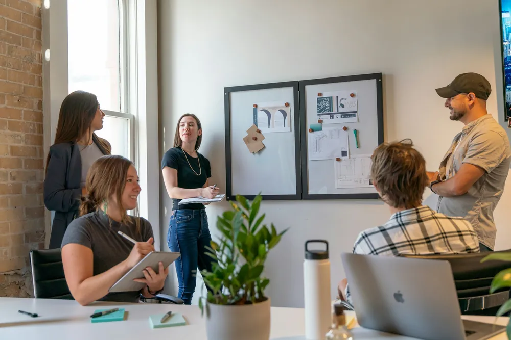 Un atelier collaboratif dans un bureau ensoleillé, devant un tableau d’affichage